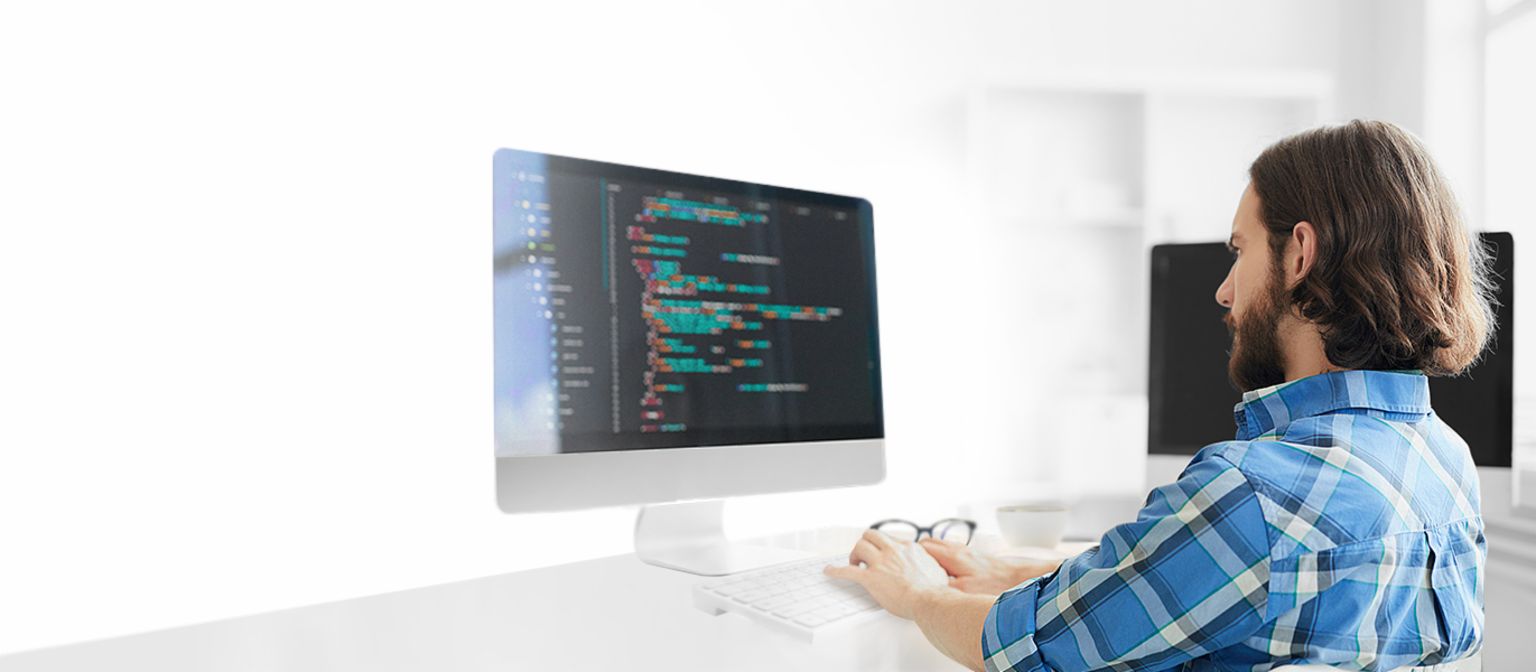 Man sitting on a computer looking at the screen and programming