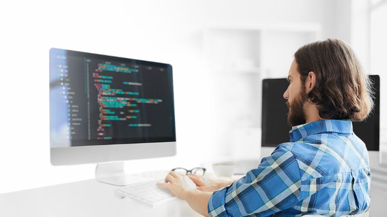 Man sitting on a computer looking at the screen and programming