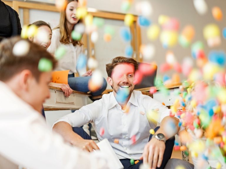 Agiles Arbeiten: Mitarbeiterinnen und Mitarbeiter mit vielen bunten Bällen.
